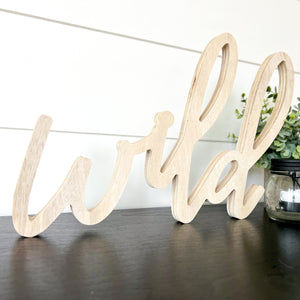 Hand-lettered "wild" wood sign sitting on table