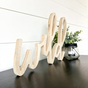 Hand-lettered "wild" wood sign sitting on table